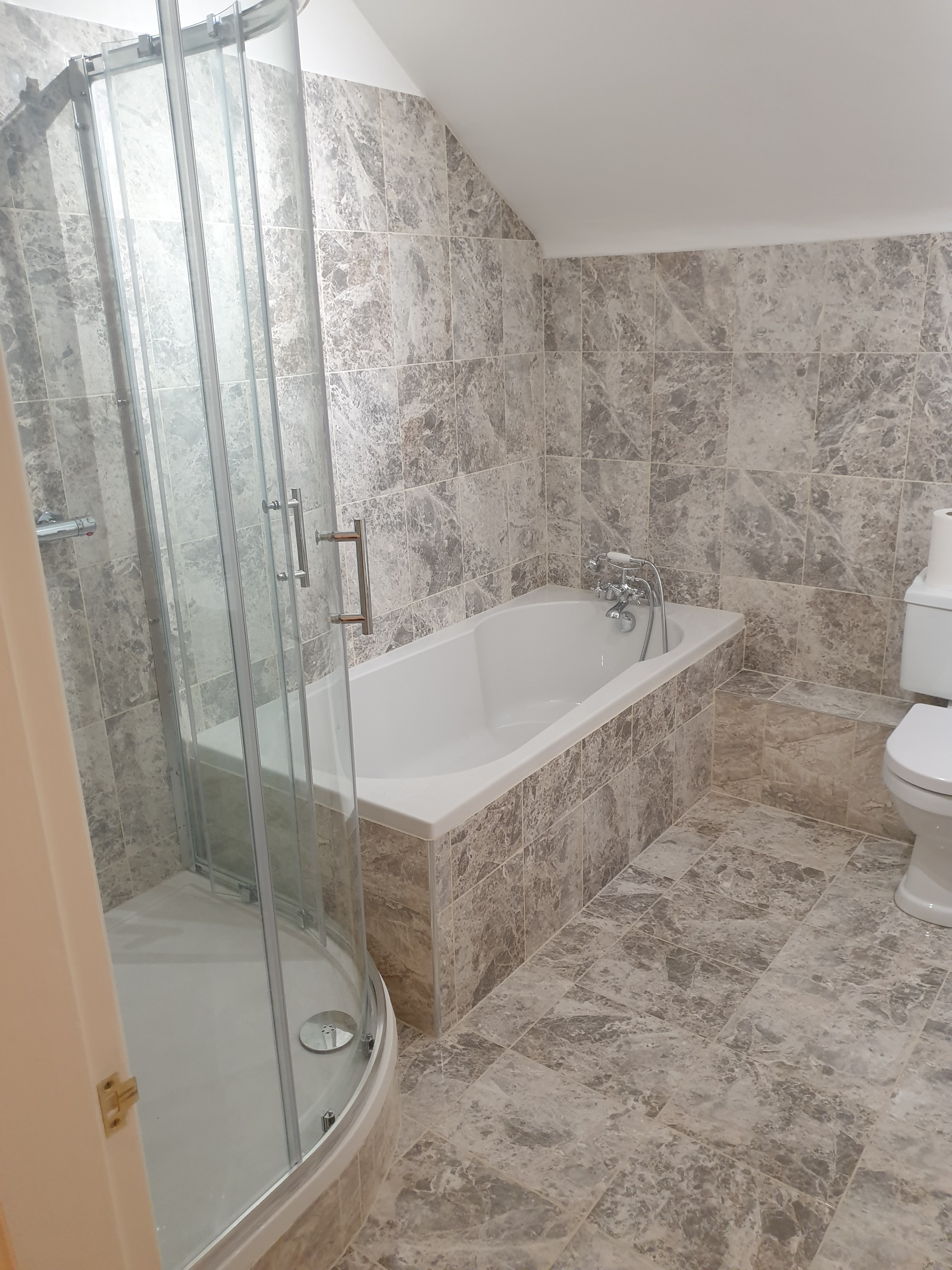 Full bathroom refurbishment with updated plumbing, a new bath and separate shower. Marble-effect tiles carry across the walls, floor and bath panel.