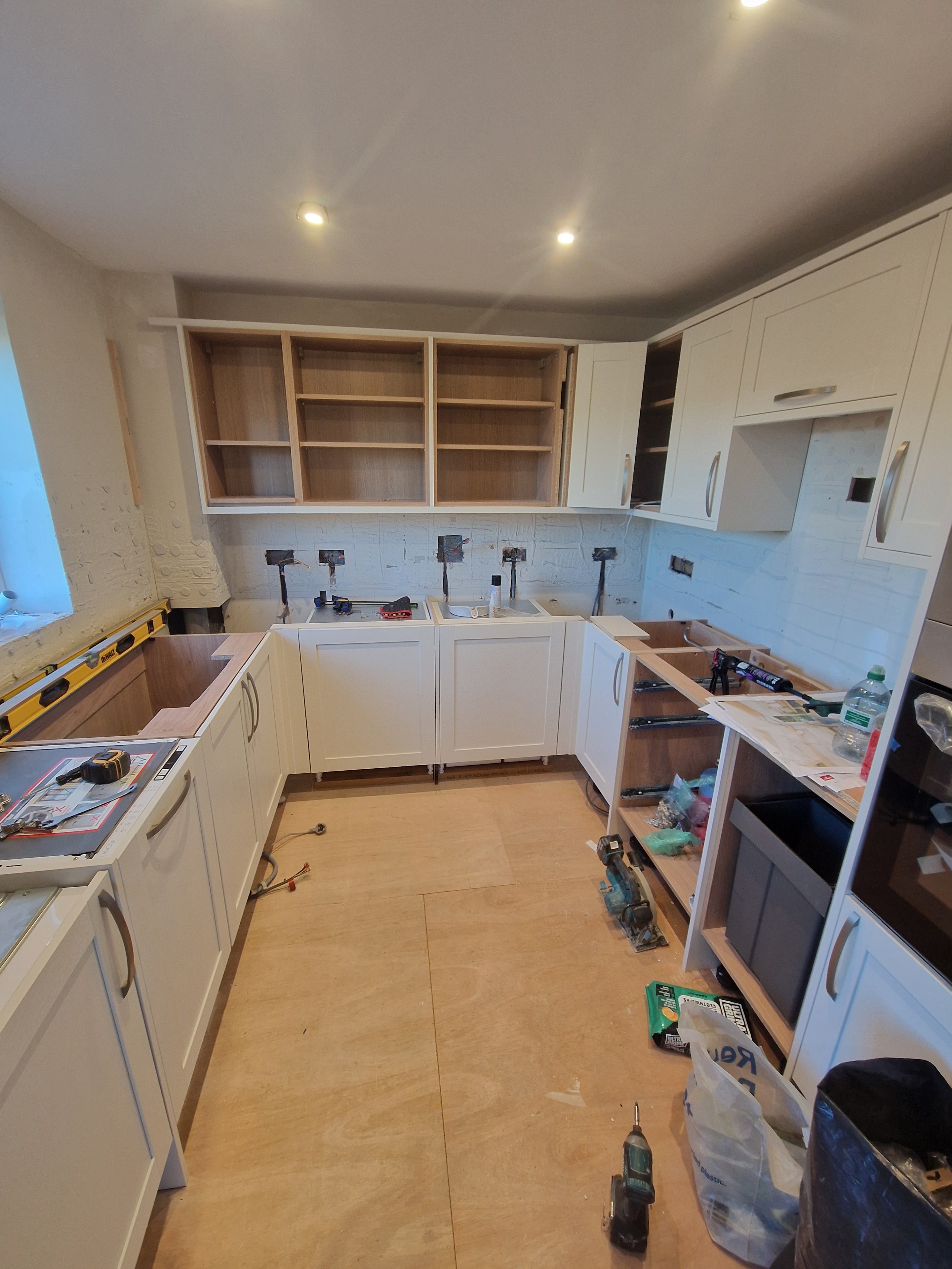 Kitchen renovation in progress, with the new cabinets fitted and work underway on the worktops and splashback.