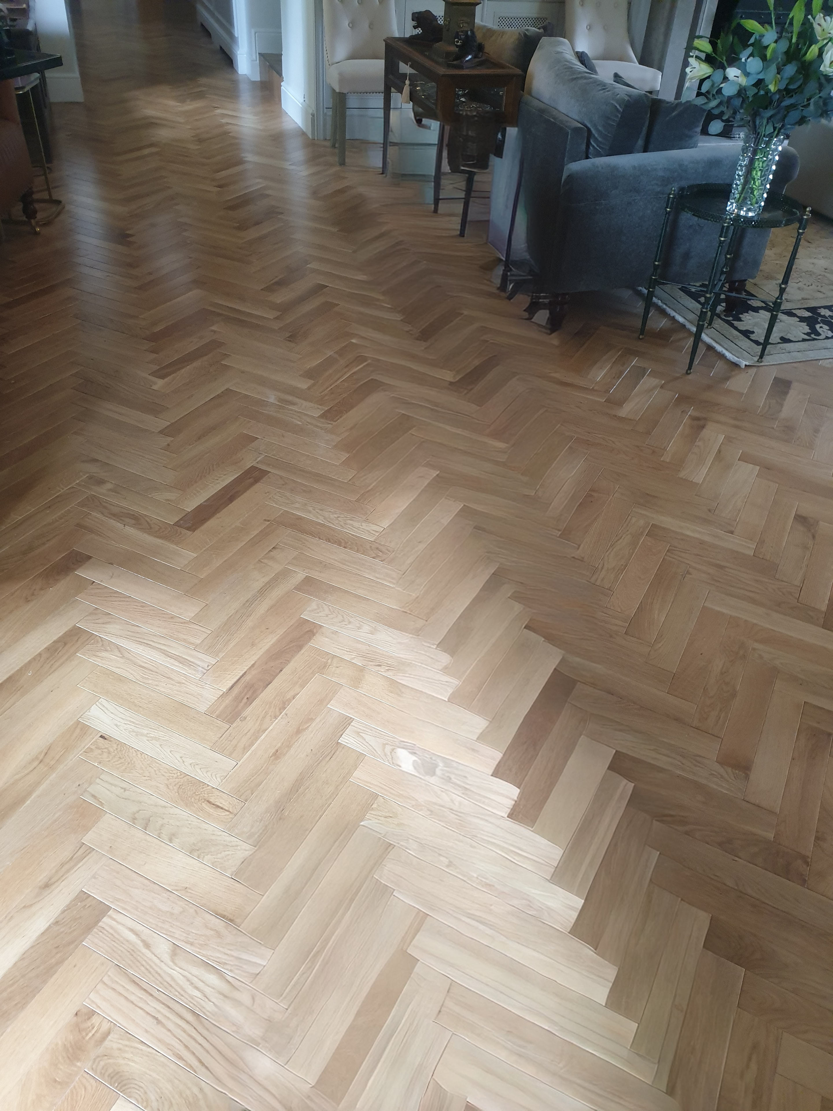 Wood flooring laid in a herringbone pattern, creating a warm, detailed finish across the room.