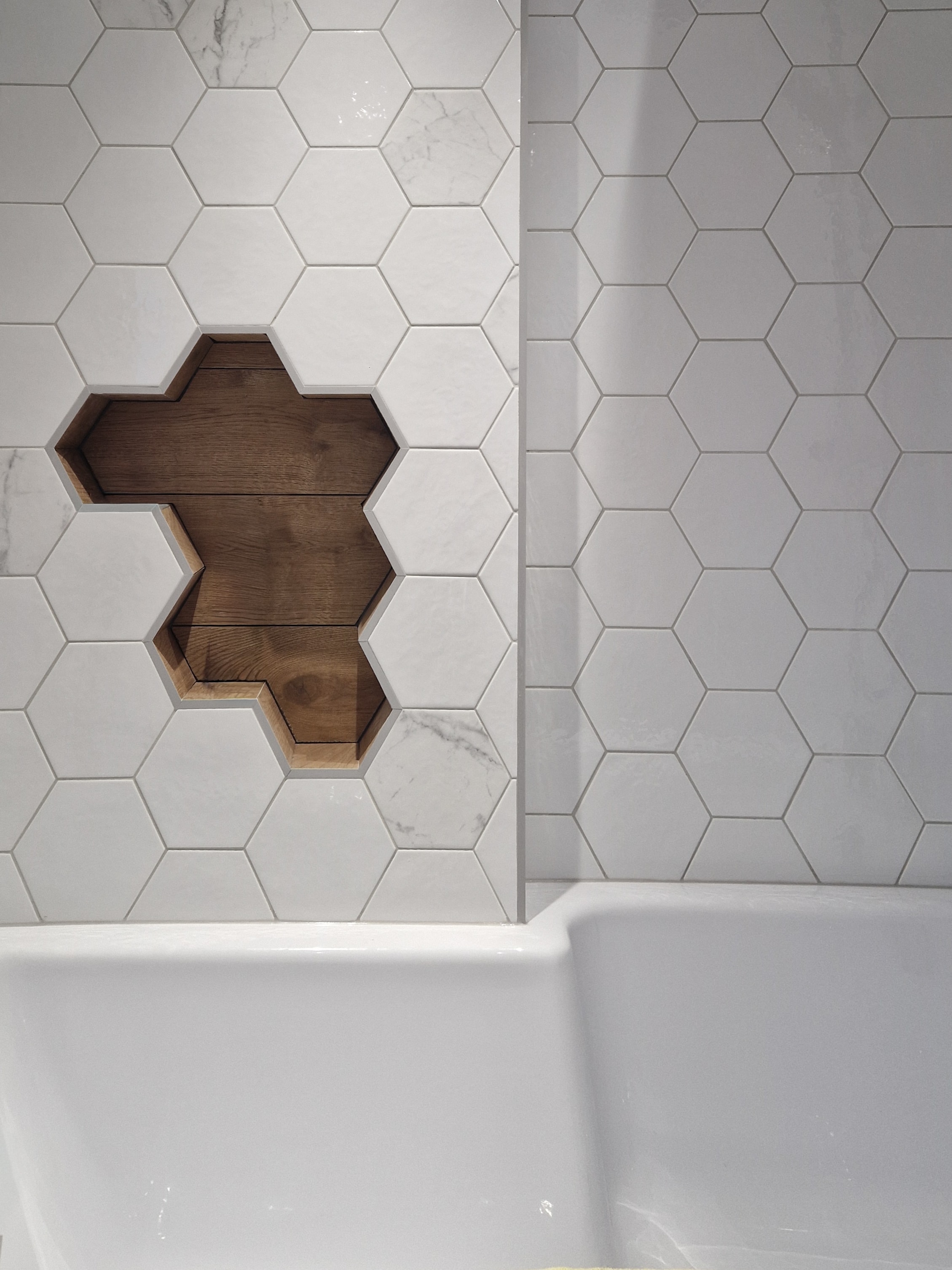 Custom recessed shelving built into the hexagonal tiled wall, with a warm timber finish inside.